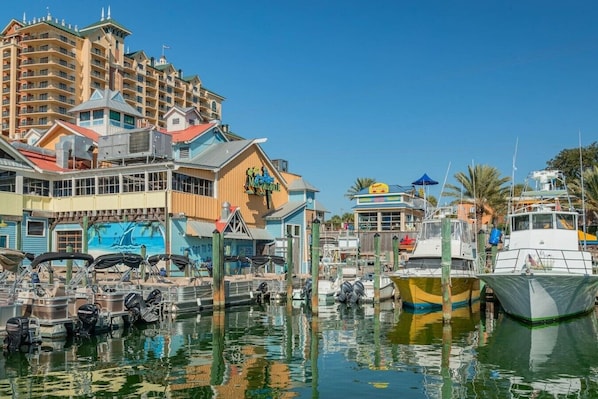 A marina with boats docked, a building with a mural, and a multi-story hotel in the background.