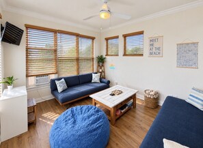 A cozy living room with a blue sofa, a wooden coffee table, and a blue bean bag.