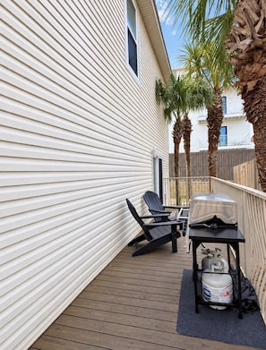 A deck with a grill, two chairs, and a gas cylinder.