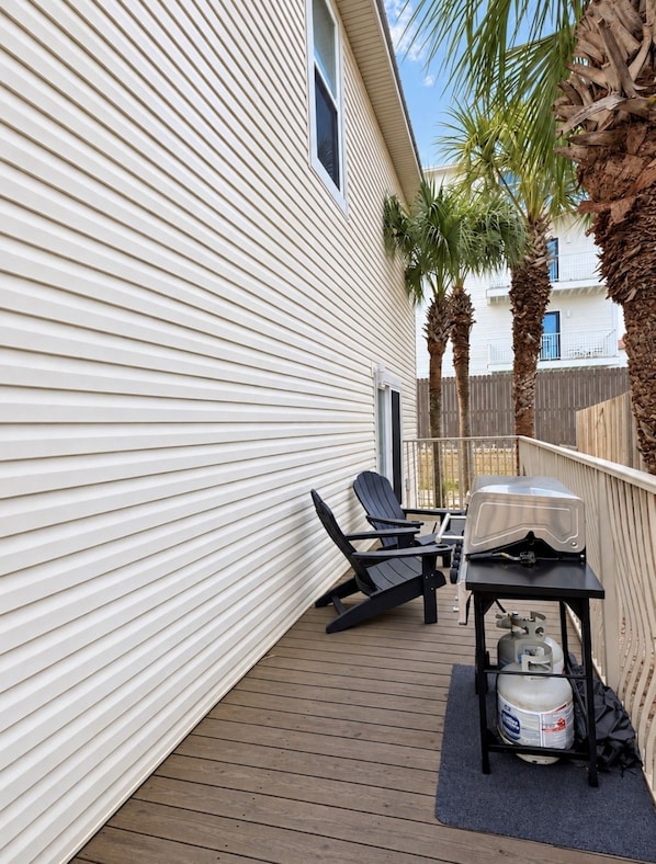 A deck with a grill, two chairs, and a gas cylinder.