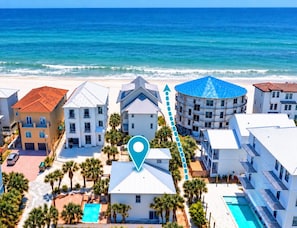 A beachfront hotel complex with multiple buildings, a swimming pool, and a view of the ocean.