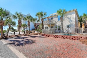 A residential building with a pool, surrounded by palm trees and a brick pathway.