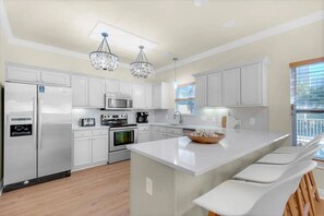 A modern kitchen with white cabinetry, stainless steel appliances, a central island, and pendant lighting. - Luxury 6BR, Private Pool, Beach Access, Sleeps 20 (Destin)