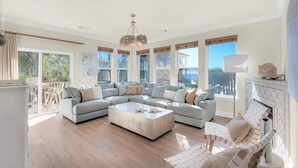 A spacious living room with a large L-shaped sectional sofa, a coffee table, and a fireplace. - Luxury 6BR, Private Pool, Beach Access, Sleeps 20 (Destin)