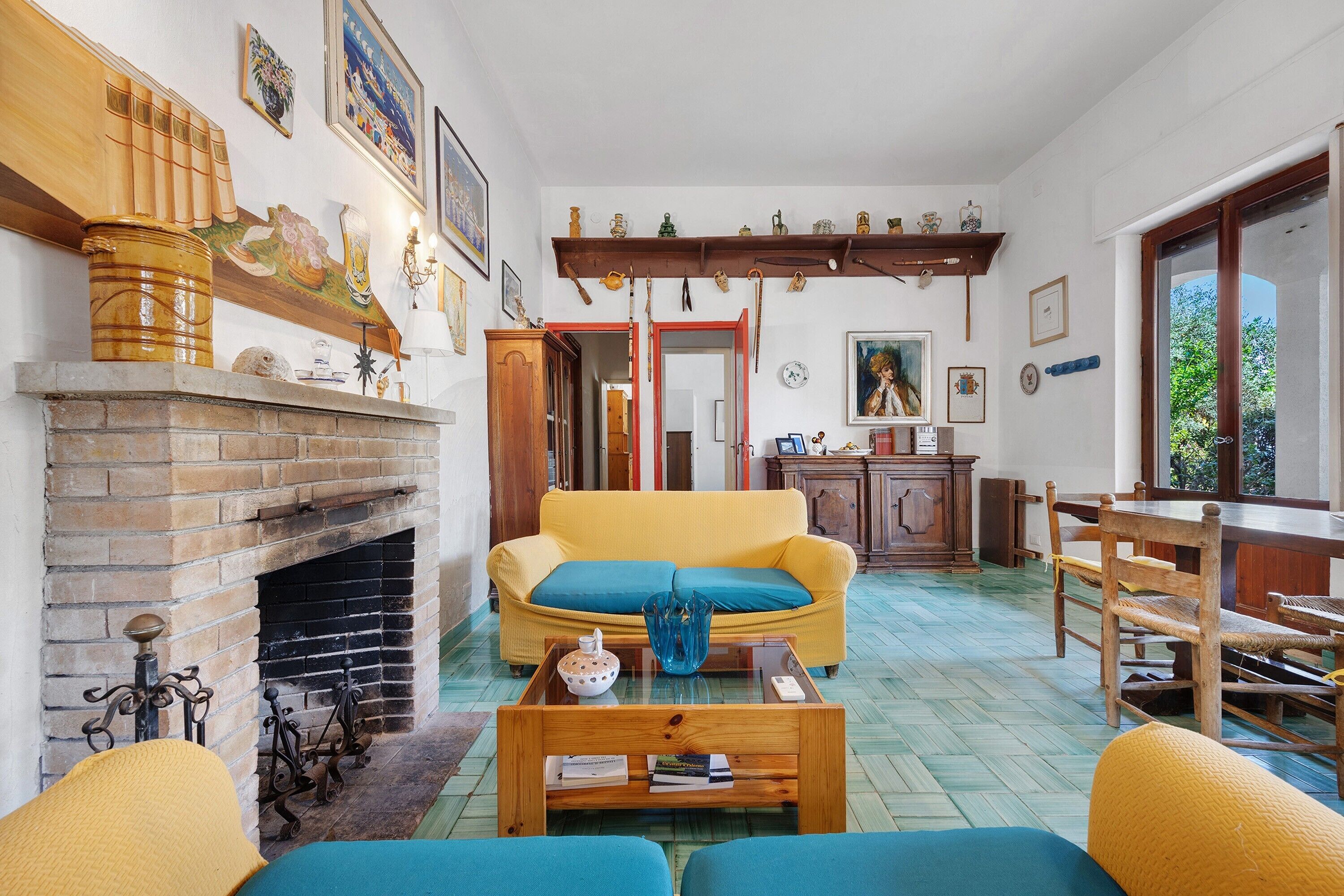 Una sala de estar con chimenea, un sofá amarillo, una mesa de centro de madera y un comedor con mesa y sillas de madera.