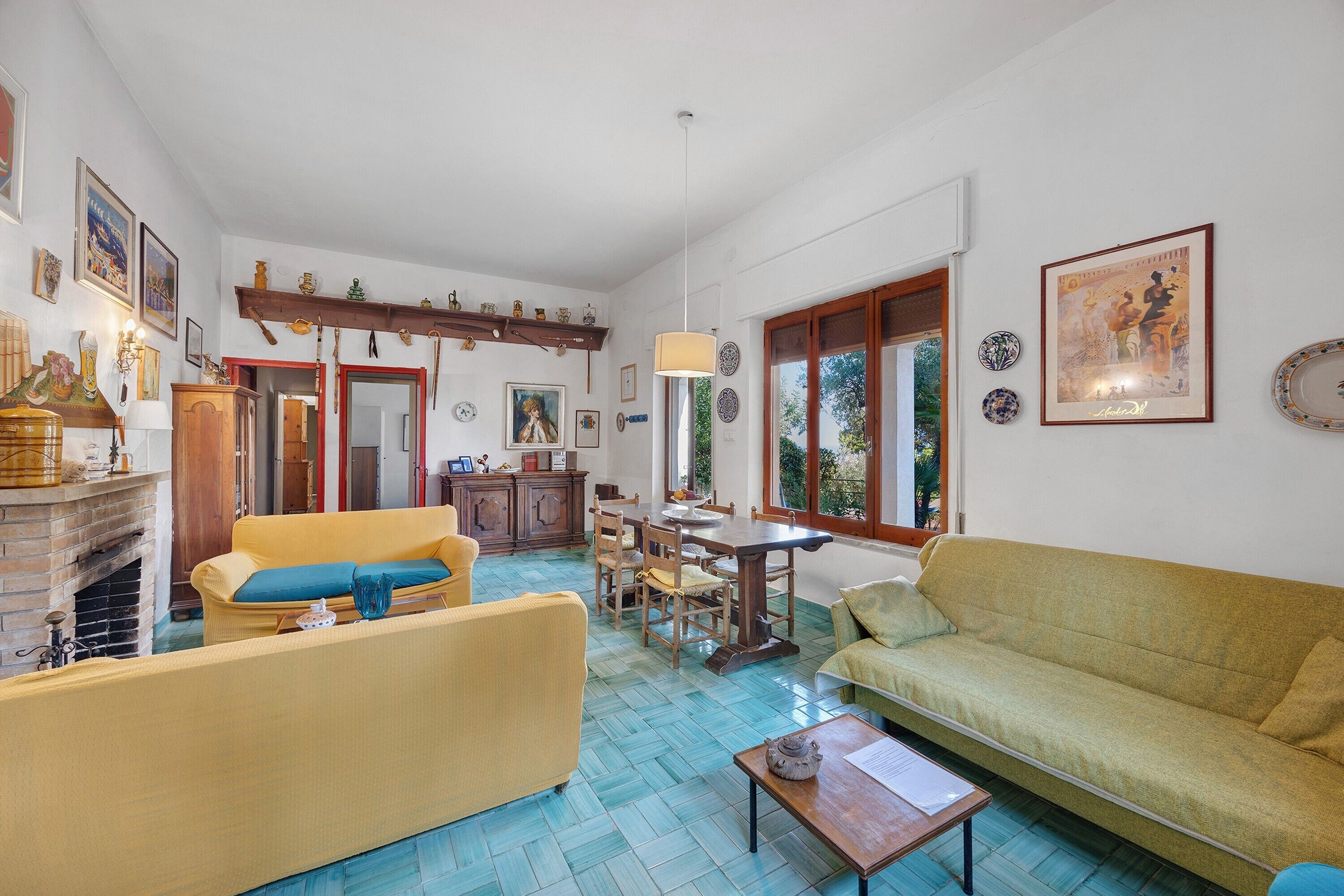 Een ruime woonkamer met een open haard, een eethoek en uitzicht op de omgeving.