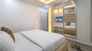 A modern bedroom with a bed, a TV mounted on a wall, and a wardrobe. - Cozy 1-Bedroom Apartment in Lekki 1 with Fast Wi-Fi & 24/7 Power (Lagos)