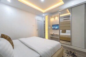 Ein modernes Schlafzimmer mit einem Bett, einem an der Wand befestigten Fernseher und einem Kleiderschrank.