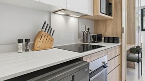 Et moderne køkken med en sort induktionskogetop, en træ-knivblok og indbyggede hårde hvidevarer.