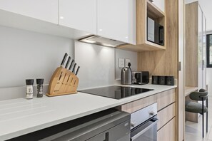 Eine moderne Küche mit einem schwarzen Induktionskochfeld, einem Holzmesserblock und integrierten Geräten.