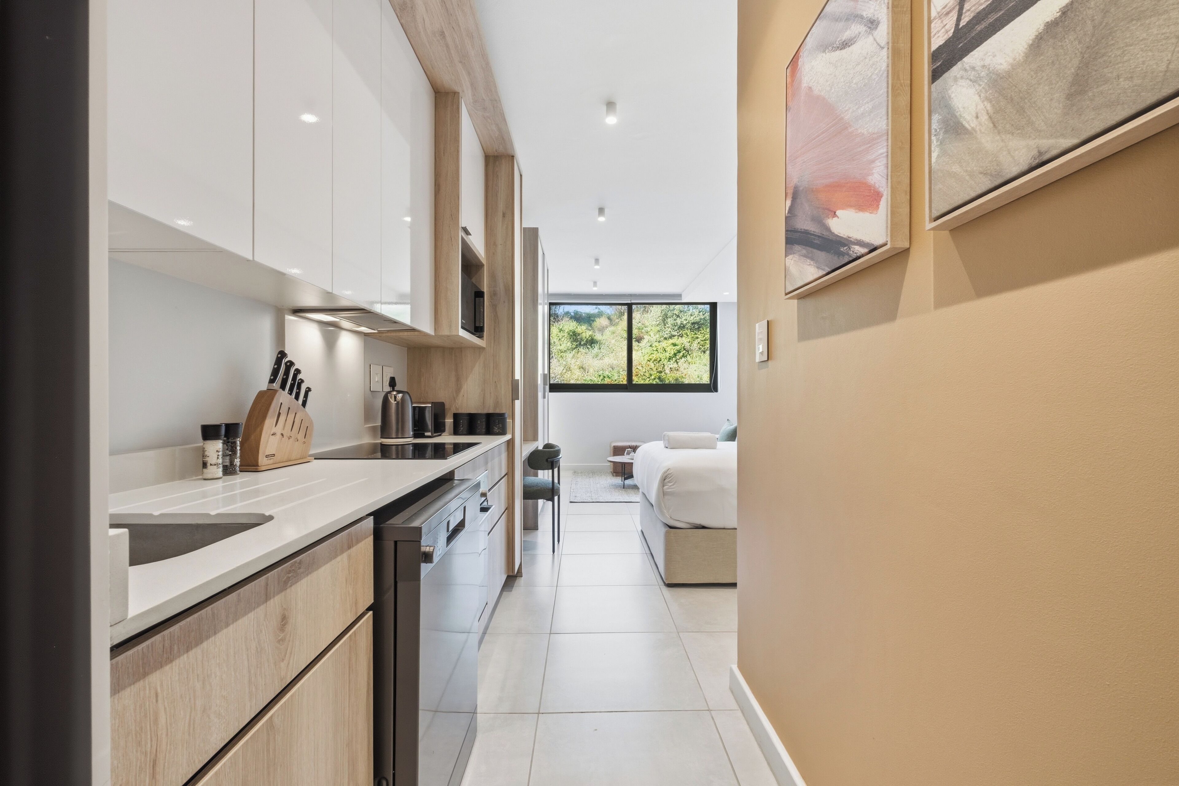 A modern kitchen with white cabinets, a wooden countertop, and a view into the living area.