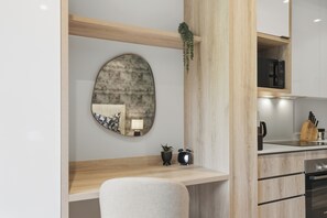 Eine moderne Küche mit Holztischplatte, einem runden Spiegel, einem kleinen Tisch mit Lampe und einer Mikrowelle.