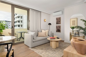 A modern living room with a grey sofa, a round coffee table, and a view of a building through a sliding door. - Dolce Vita, Stylish Sea Point Retreat (Cape Town)