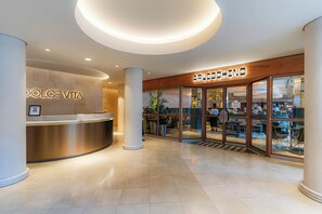 Un vestíbulo de hotel con una recepción que dice 'Dolce Vita' y un restaurante llamado 'Arlecchino'.
