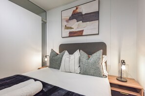 Une chambre moderne avec un grand lit, deux lampes de chevet et un tableau abstrait accroché au mur.