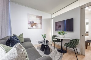 Un salon moderne avec un canapé gris, une table basse et un coin repas comprenant des chaises et une petite table.