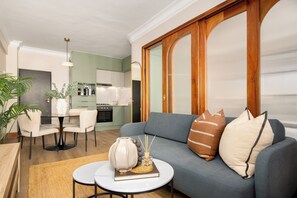 A modern living room with a grey sofa, a small round coffee table, and a dining area with a white table and chairs. - Charlie and the Chairman, Stylish CBD Apartment (Cape Town)