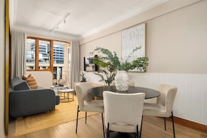 A modern living room with a dining area, featuring a sofa, chairs, a coffee table, and a vase with plants. - Charlie and the Chairman, Stylish CBD Apartment (Cape Town)