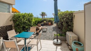 A patio area with outdoor furniture, a table, and a blue umbrella. - Le Jardin de La Plage - Climatisé et plage à 100 m (Canet-en-Roussillon)