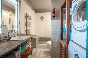 Ein kleines Badezimmer mit Waschbecken, Spiegel, Handtuchhalter und einer Waschmaschine.