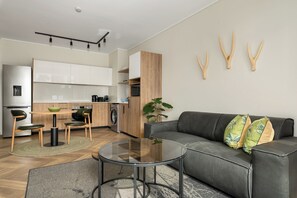 Een moderne woonruimte met een bank, salontafel en een eethoek met stoelen en een tafel.