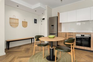 Eine moderne Küche mit einem runden Tisch, zwei Stühlen, einer Bank und einem Bosch-Ofen.