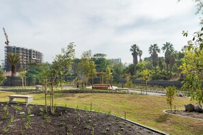 Een park met een speeltuin, een bankje en een bouw kraan op de achtergrond.