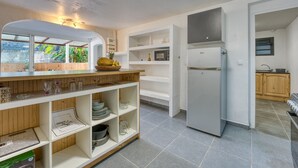 A modern kitchen with a built-in microwave, a refrigerator, and a wooden countertop. - La Case Coco - Bananes - Appartement climatisé (Saint Joseph)