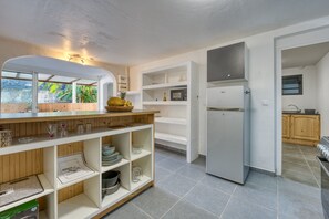 A modern kitchen with a built-in microwave, a refrigerator, and a wooden countertop. - La Case Coco - Bananes - Appartement climatisé (Saint Joseph)
