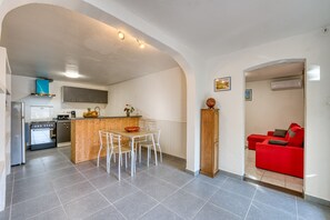 A compact kitchen with a dining area, a red sofa, and a wooden cabinet. - La Case Coco - Bananes - Appartement climatisé (Saint Joseph)