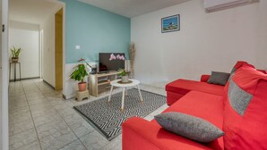 A living room with a red sofa, a TV, and a small coffee table. - La Case Coco - Bananes - Appartement climatisé (Saint Joseph)