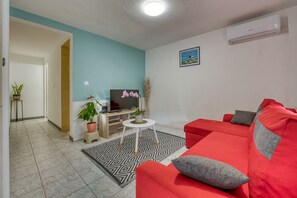 A living room with a red sofa, a TV, and a small coffee table. - La Case Coco - Bananes - Appartement climatisé (Saint Joseph)