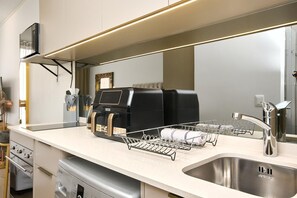A modern kitchen with a stainless steel sink, a coffee machine, and a dish drying rack. - Effortless Luxury in Rosebank (Johannesburg)