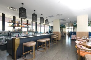 A bar area with stools, a counter, and shelves stocked with bottles. - Effortless Luxury in Rosebank (Johannesburg)