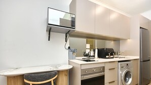 A compact kitchen with a built-in microwave, oven, and washing machine. - Effortless Luxury in Rosebank (Johannesburg)