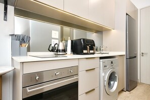 A modern kitchen with a built-in oven, a coffee maker, a toaster, and a washing machine. - Effortless Luxury in Rosebank (Johannesburg)