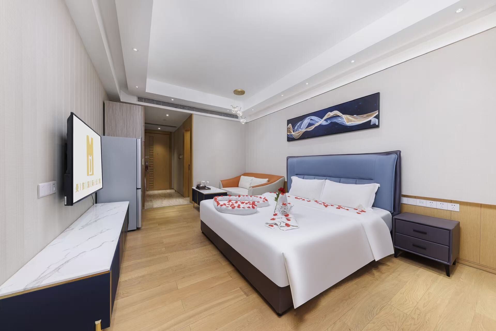 Quarto de hotel com uma cama, mesa de cabeceira e televisão fixada na parede.