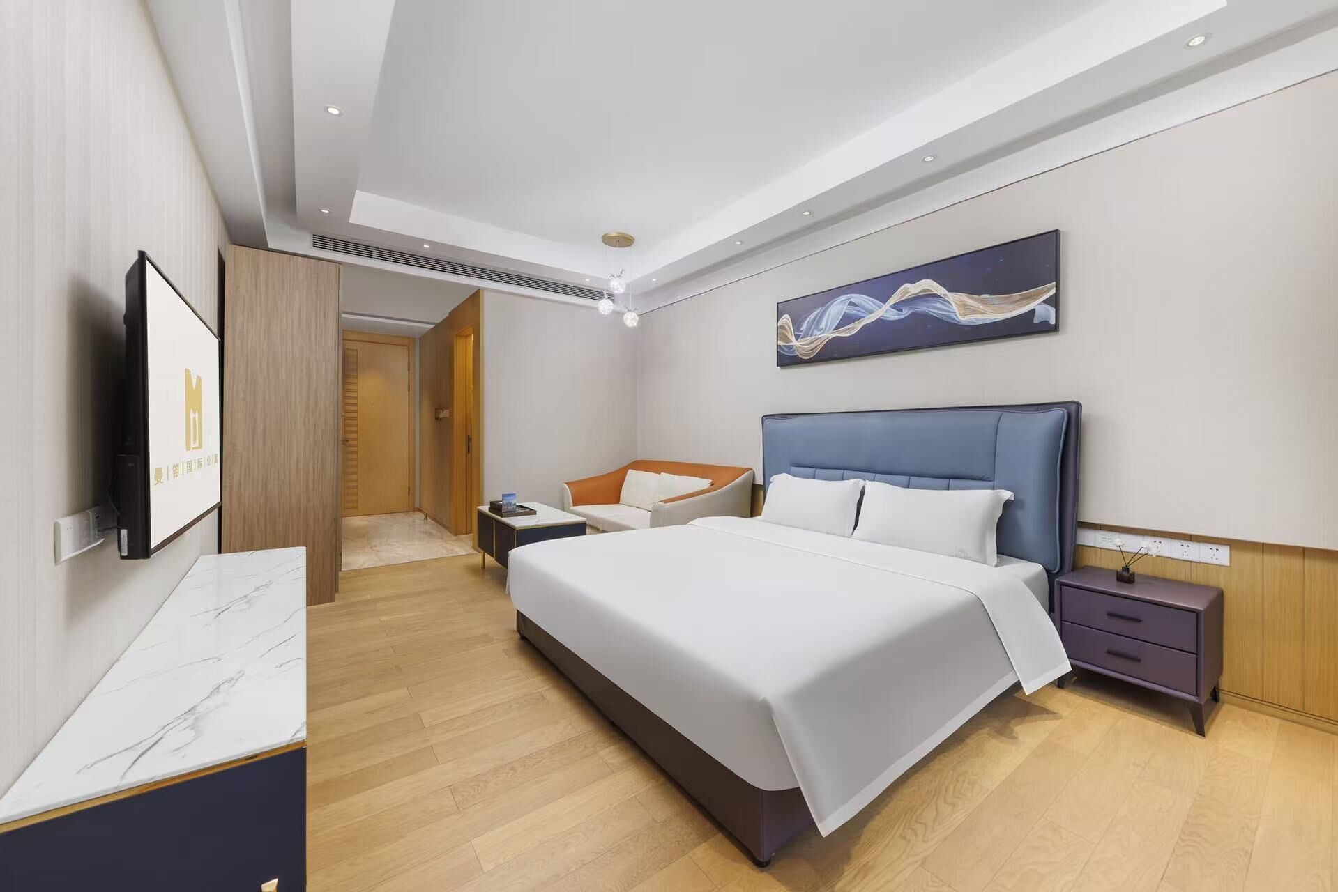 A modern hotel room with a large bed, a bedside table, a nightstand, a TV, and a painting on the wall.