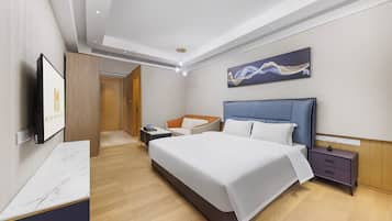 A modern hotel room with a large bed, a bedside table, a nightstand, a TV, and a painting on the wall.