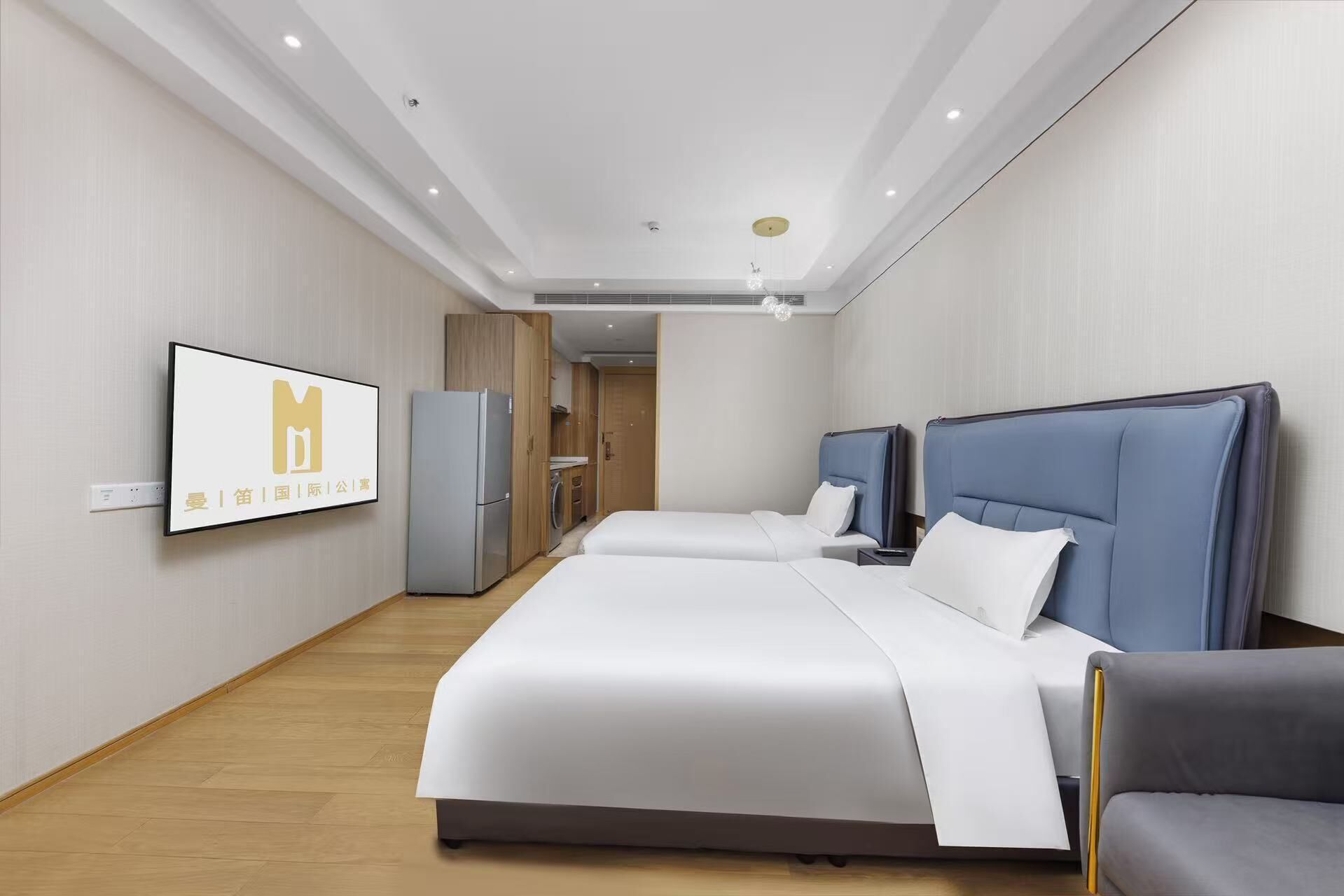 A hotel room with a large bed, a desk, a chair, a wardrobe, and a television mounted on the wall.