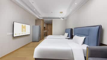 A hotel room with a large bed, a desk, a chair, a wardrobe, and a television mounted on the wall.