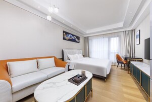 Una camera d'albergo con un letto, un divano, una scrivania e un tavolino in marmo.