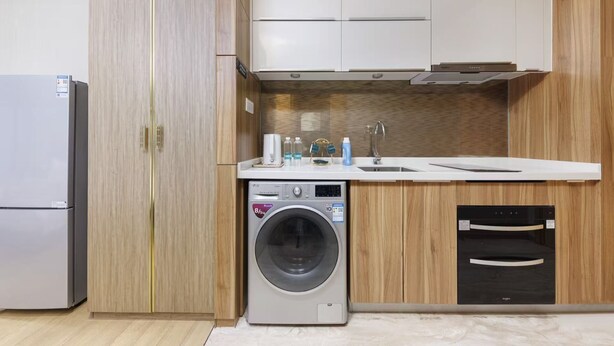 Une cuisine compacte équipée d’un lave-linge, d’un four encastré et d’un évier.