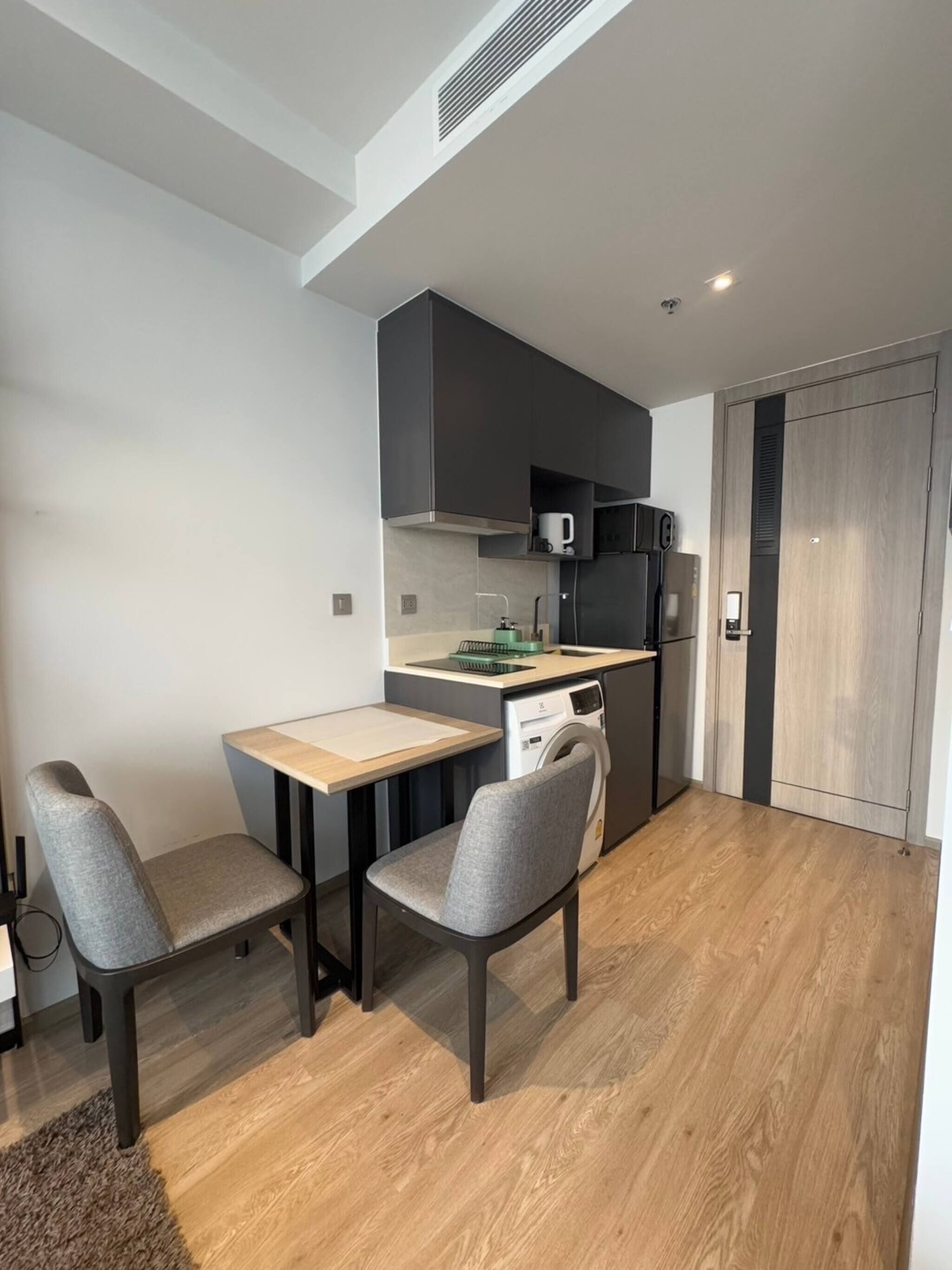 A compact kitchen with a microwave, dishwasher, and a small dining area with two chairs and a table.