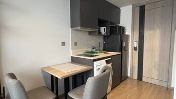 A compact kitchen with a microwave, dishwasher, and a small dining area with two chairs and a table.