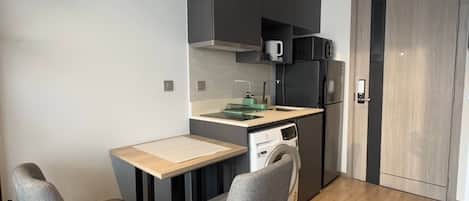 A compact kitchen with a microwave, dishwasher, and a small dining area with two chairs and a table.