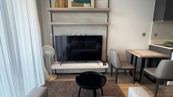 A modern living room with a sofa, a TV, and a dining area.