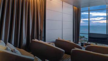 Une chambre d’hôtel dotée d’une grande fenêtre, d’un téléviseur à écran plat et d’un coin salon avec des canapés et une table basse.