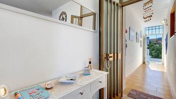 A hallway with a white wall, a door with a decorative glass panel, and a small table with a notebook and a decorative item.