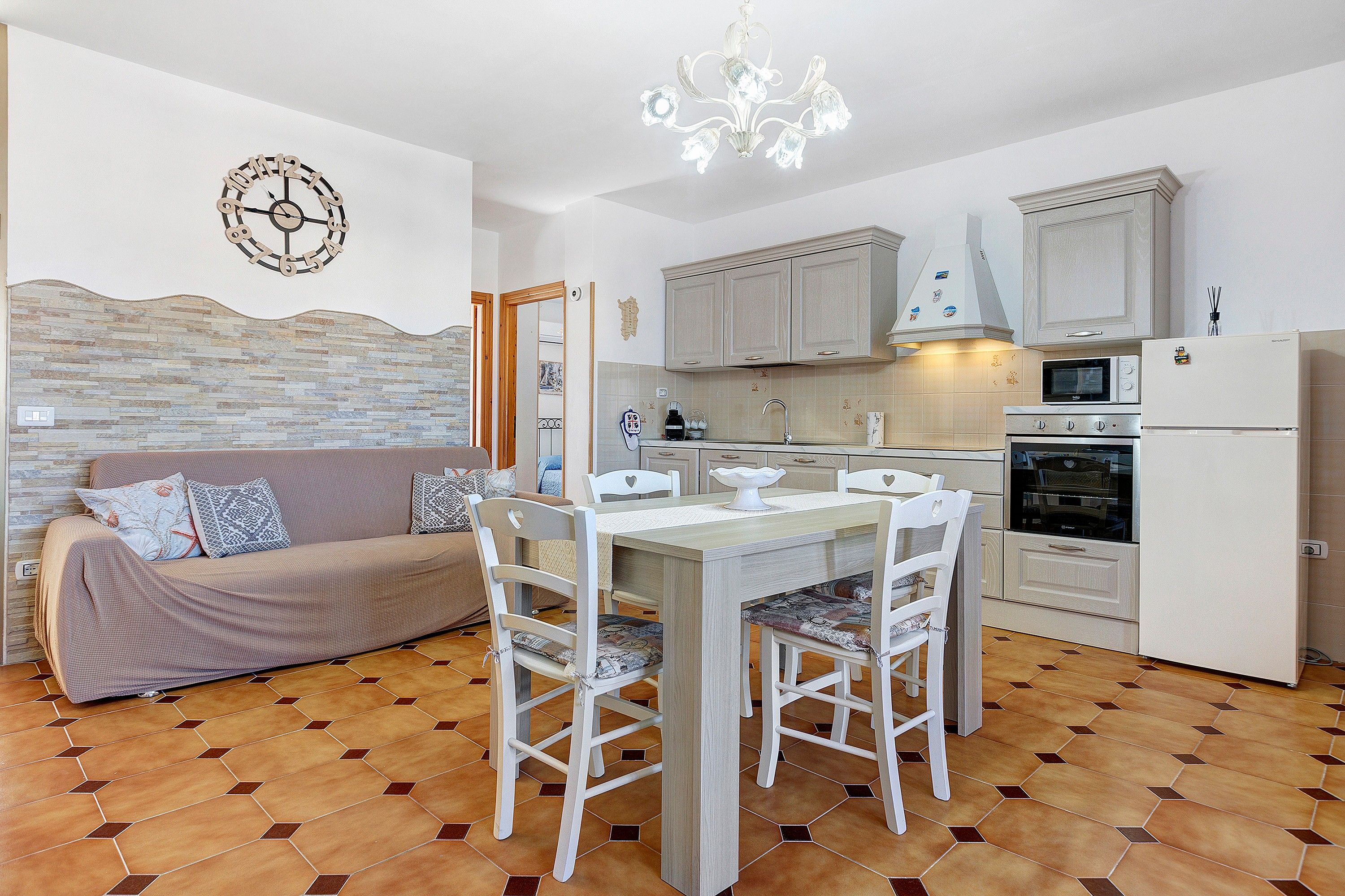 Un ambiente compatto con angolo ristoro, angolo cottura e divano con cuscini decorati.